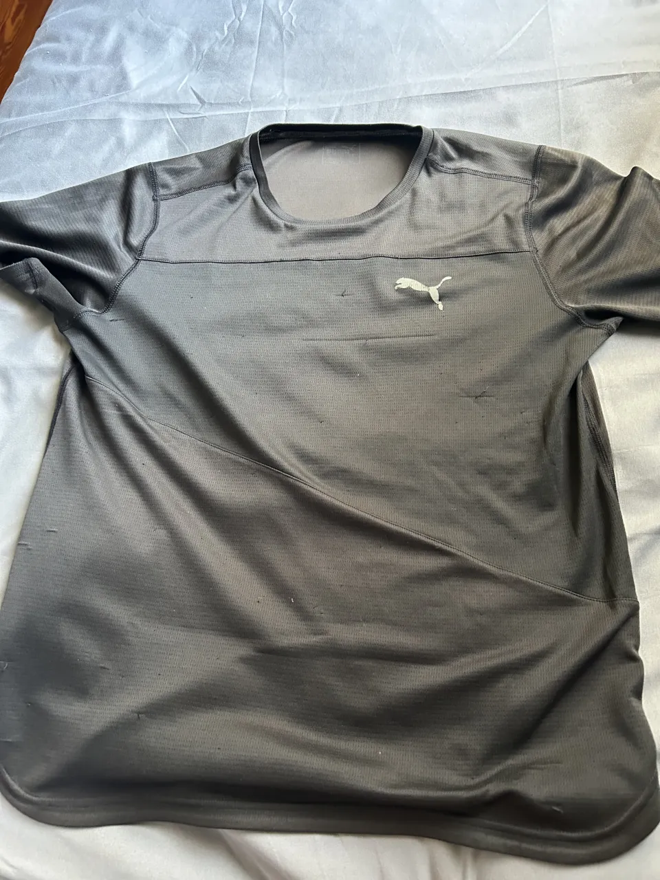 Remera deportiva negra, marca puma de manga corta, ideal para entrenamientos. Presenta un diseño moderno con líneas diagonales y el logo de la marca en el frente. Perfecta para quienes buscan comodidad y estilo al hacer ejercicio.
