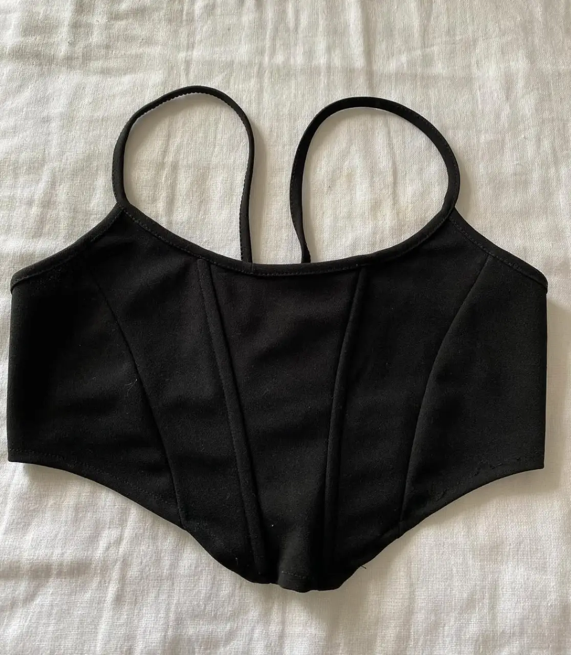 Top corset negro con breteles finos y espalda con ajuste de lazo. Ideal para looks de fiesta o salidas.