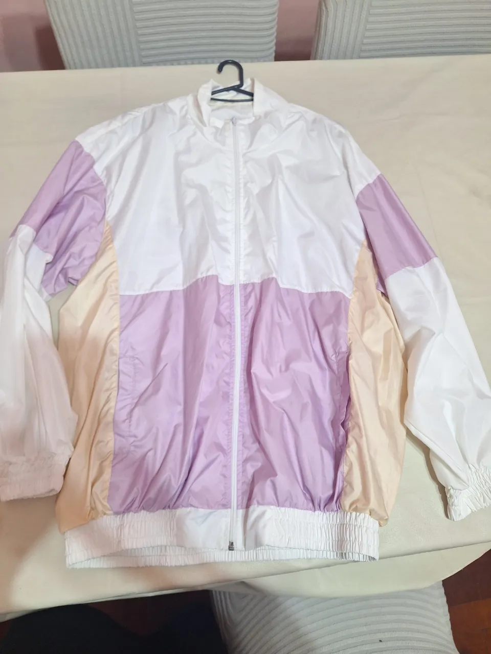 Campera deportiva para mujer, rompevientos con diseño en bloques de color blanco, rosa y beige. Ideal para actividades al aire libre o para un look casual y moderno.