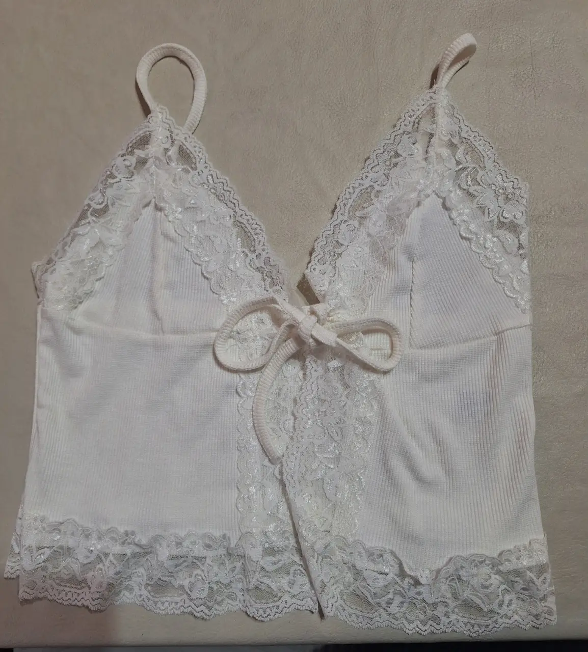 Top blanco con detalles de encaje y lazo en el frente. Ideal para un look romántico y fresco.