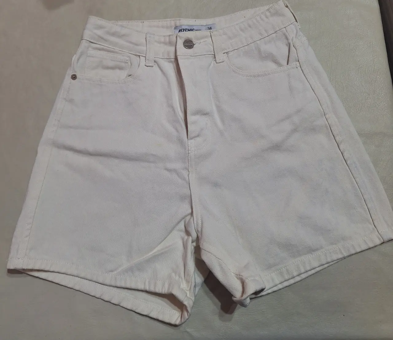 Short de jean blanco, tiro alto, con bolsillos delanteros y traseros. Ideal para un look casual y fresco. Tiene unas pequeñas manchas que ni se notan.