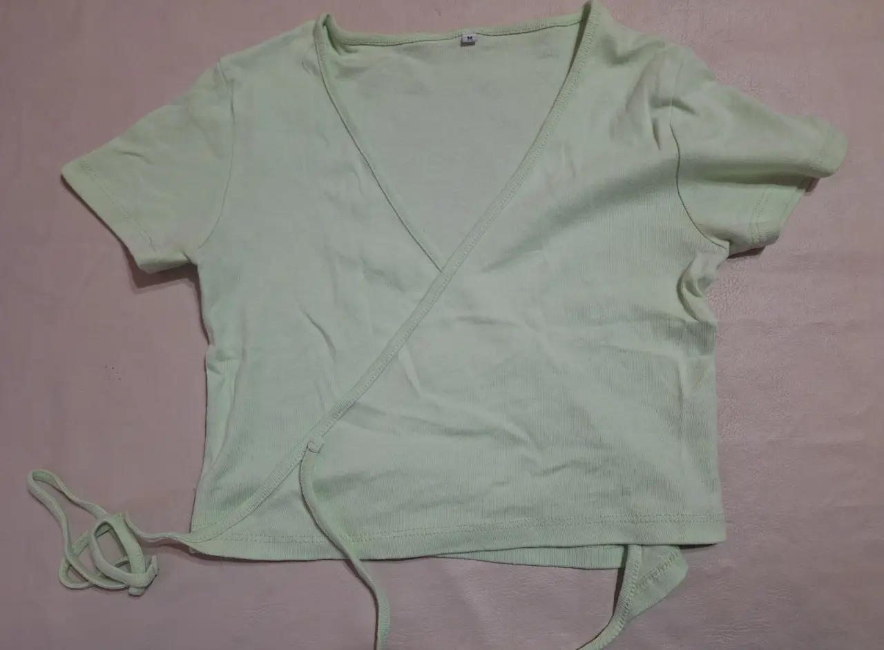 Top cruzado de mujer en color verde claro, ideal para un look fresco y moderno. Confeccionado en tela suave y cómoda, este top es perfecto para combinar con jeans, faldas o shorts. Un básico versátil para tu guardarropa.