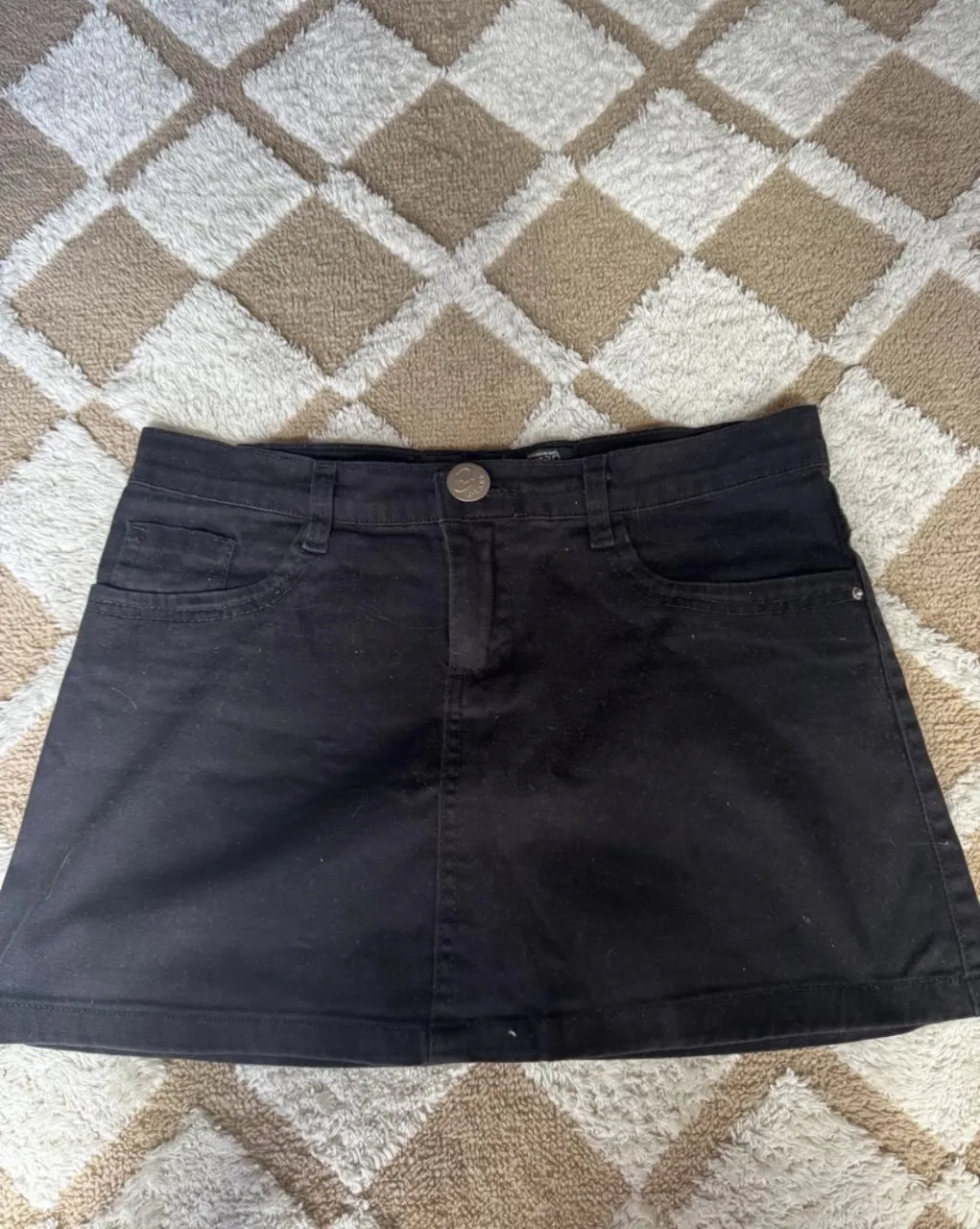 Pollera negra de jean, con bolsillos delanteros y traseros.