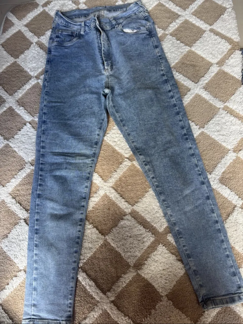 Jeans de tiro alto, color azul claro con efecto desgastado. Presentan cinco bolsillos y cierre con botón.