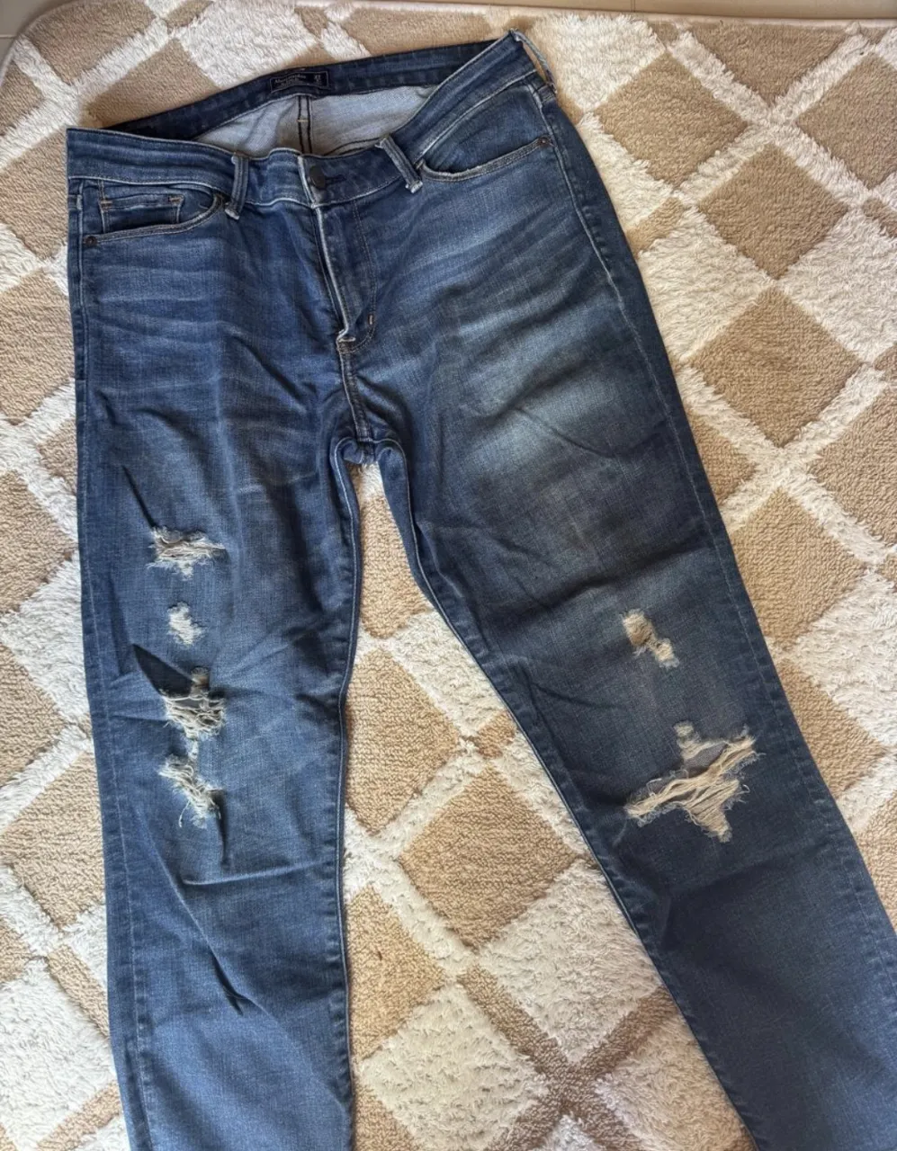 Jeans de denim azul con roturas y desgastes.