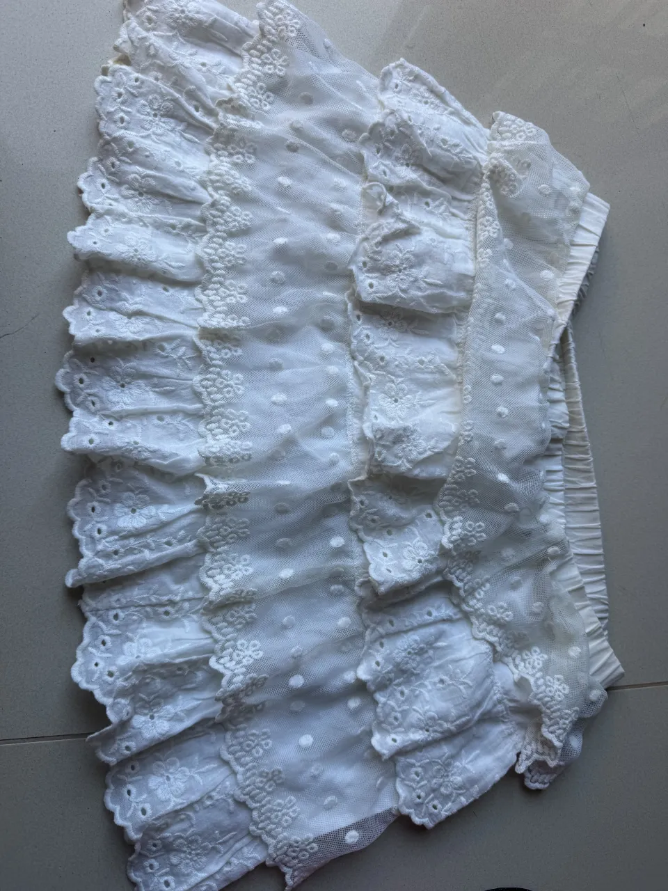 Pollera blanca con volados y detalles de bordado y puntillas. Posee elástico en la cintura.