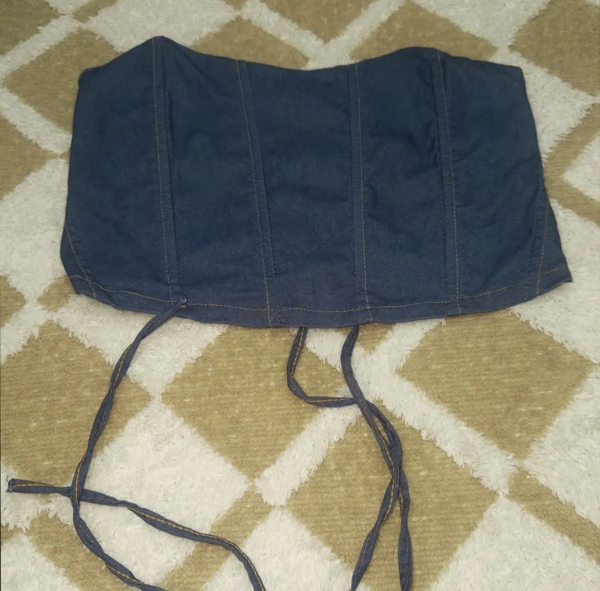 Top de jean azul con cordones para atar en la espalda. Posee costuras verticales y un diseño tipo corset.