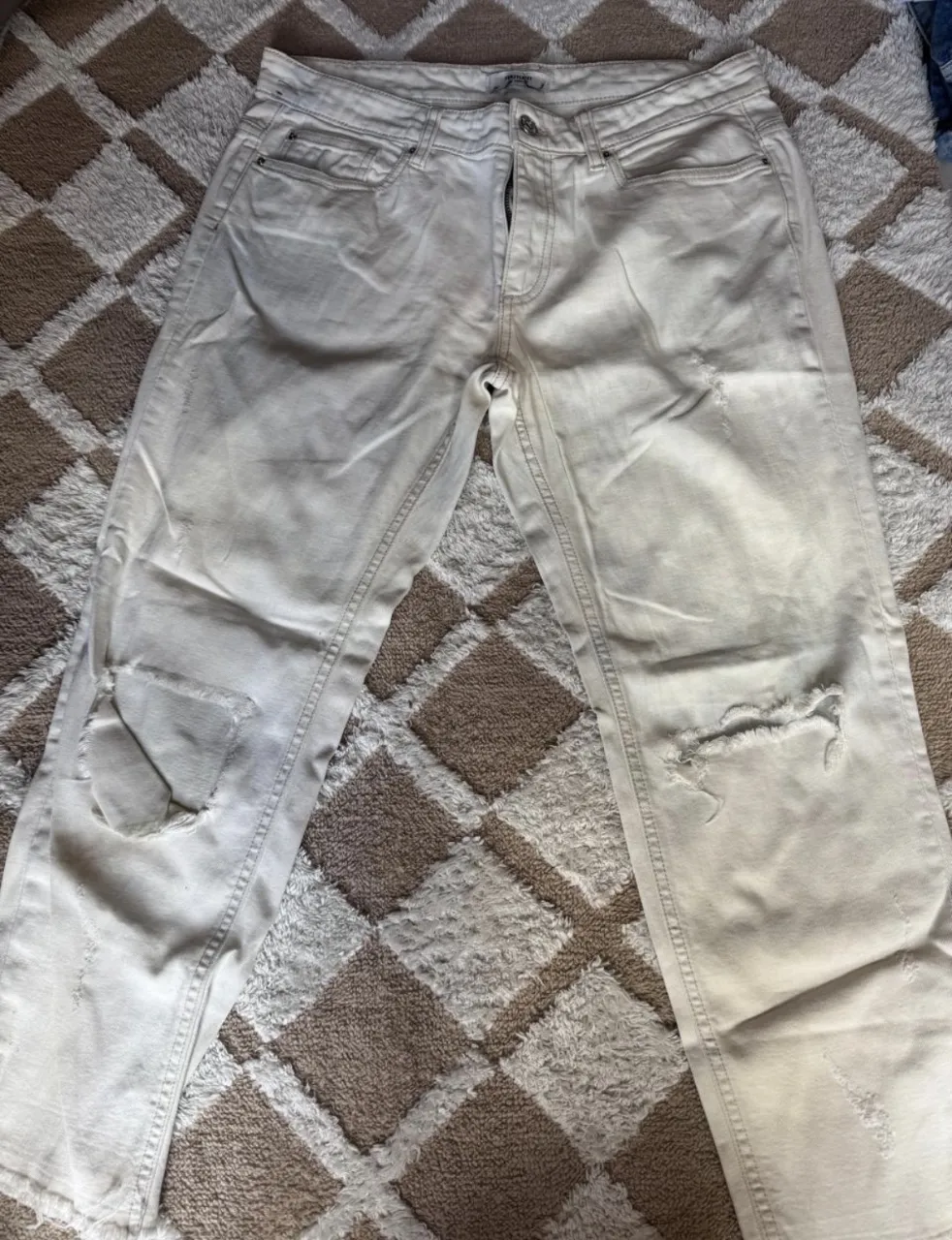 Jeans color crudo con roturas y desgastes. Cierre y botón.