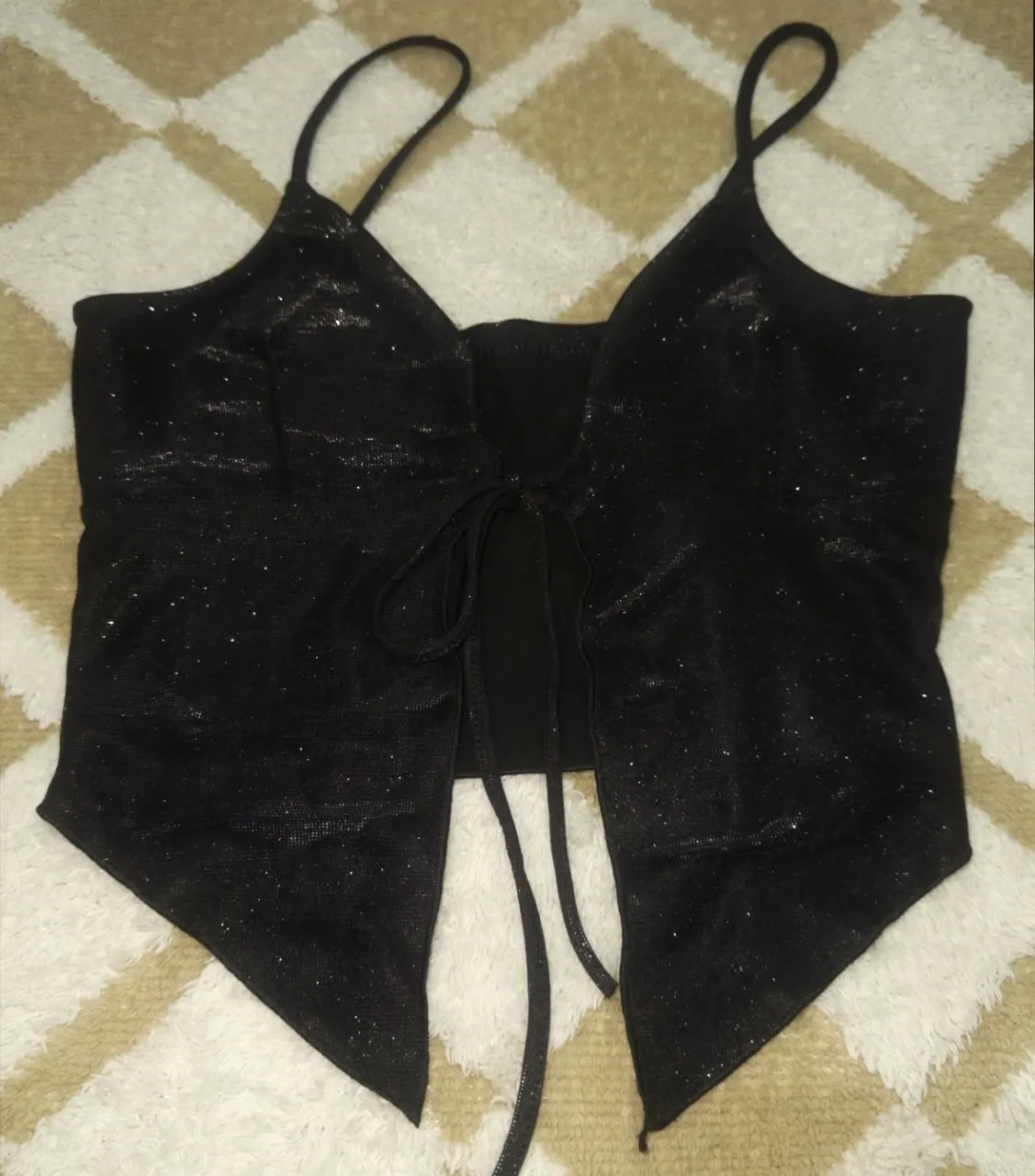 Top negro con brillos y tiras finas. Posee un lazo en la parte delantera para atar.