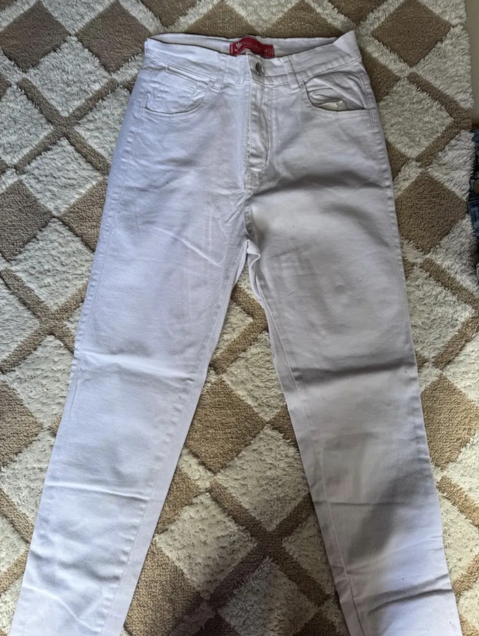 Pantalón de jean blanco, tiro alto, con bolsillos delanteros y traseros.