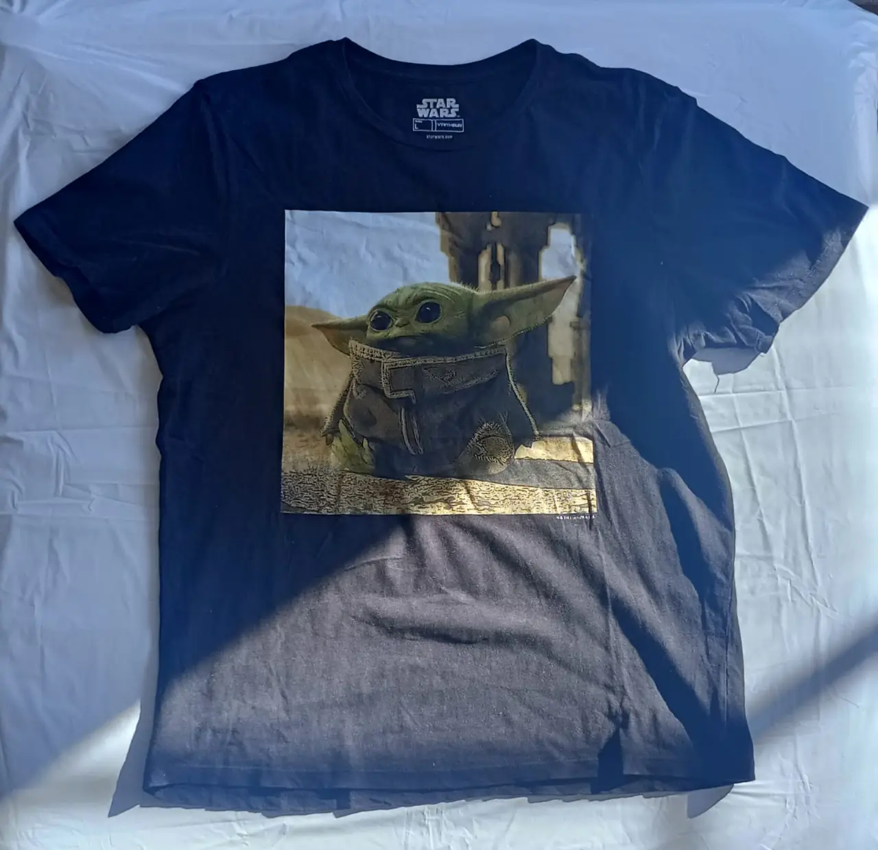 Remera negra de manga corta con estampado de Grogu (Baby Yoda) de Star Wars. Talle L, ideal para un look casual y fanático de la saga.