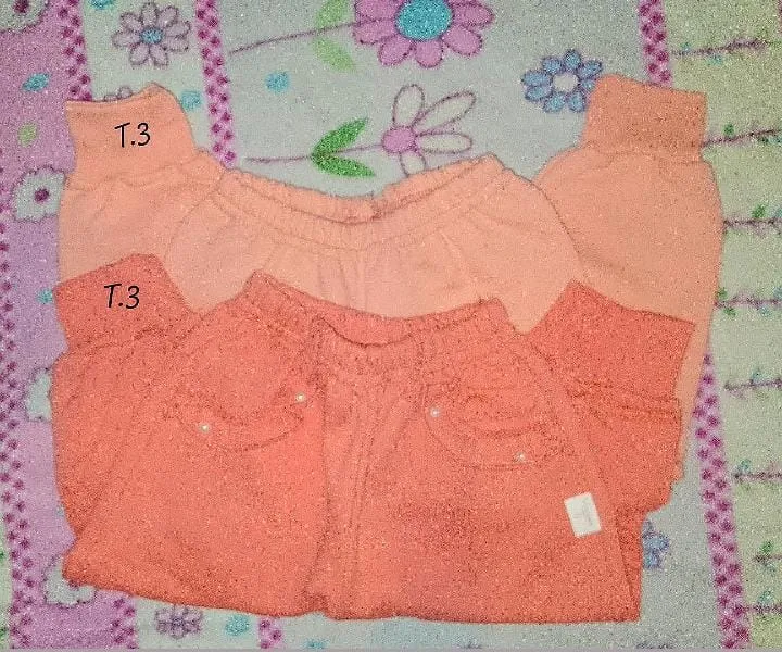 Conjunto de dos pantalones de beba, uno en tono coral y otro en tono salmón. Ambos presentan pretina elástica y detalles de pequeñas perlas bordadas en los bolsillos delanteros (Salmón). Uno de los pantalones tiene una etiqueta blanca visible.
Se vende junto o aparte 