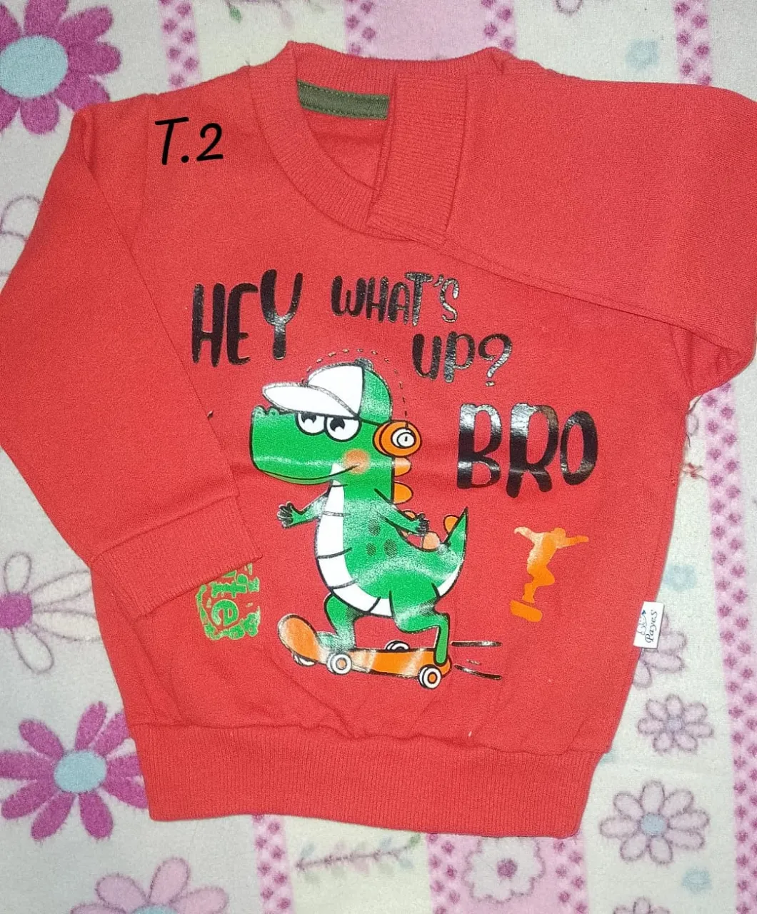 buzo de algodón color rojo con estampa de dinosaurio verde en patineta y la frase "HEY WHAT'S UP? BRO".