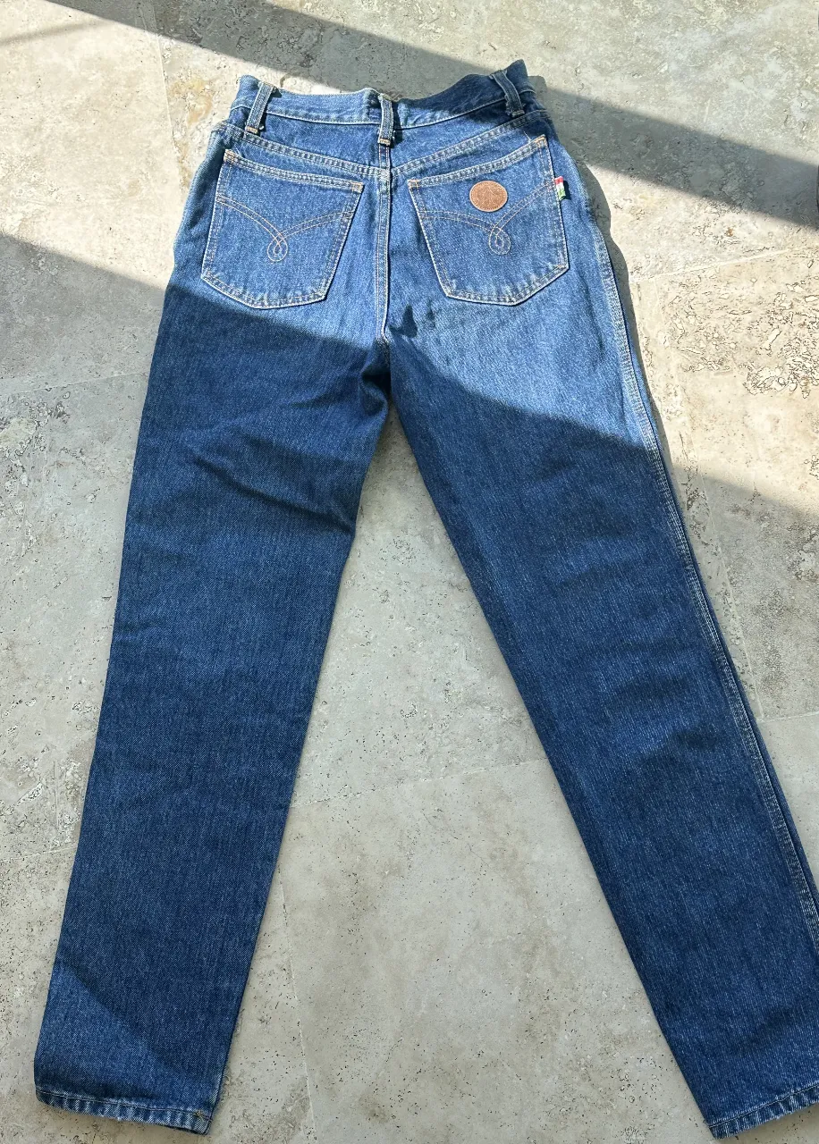 Jeans rectos de mujer, tiro alto, con detalle de etiqueta de marca en bolsillo trasero. Ideal para un look casual y versátil.