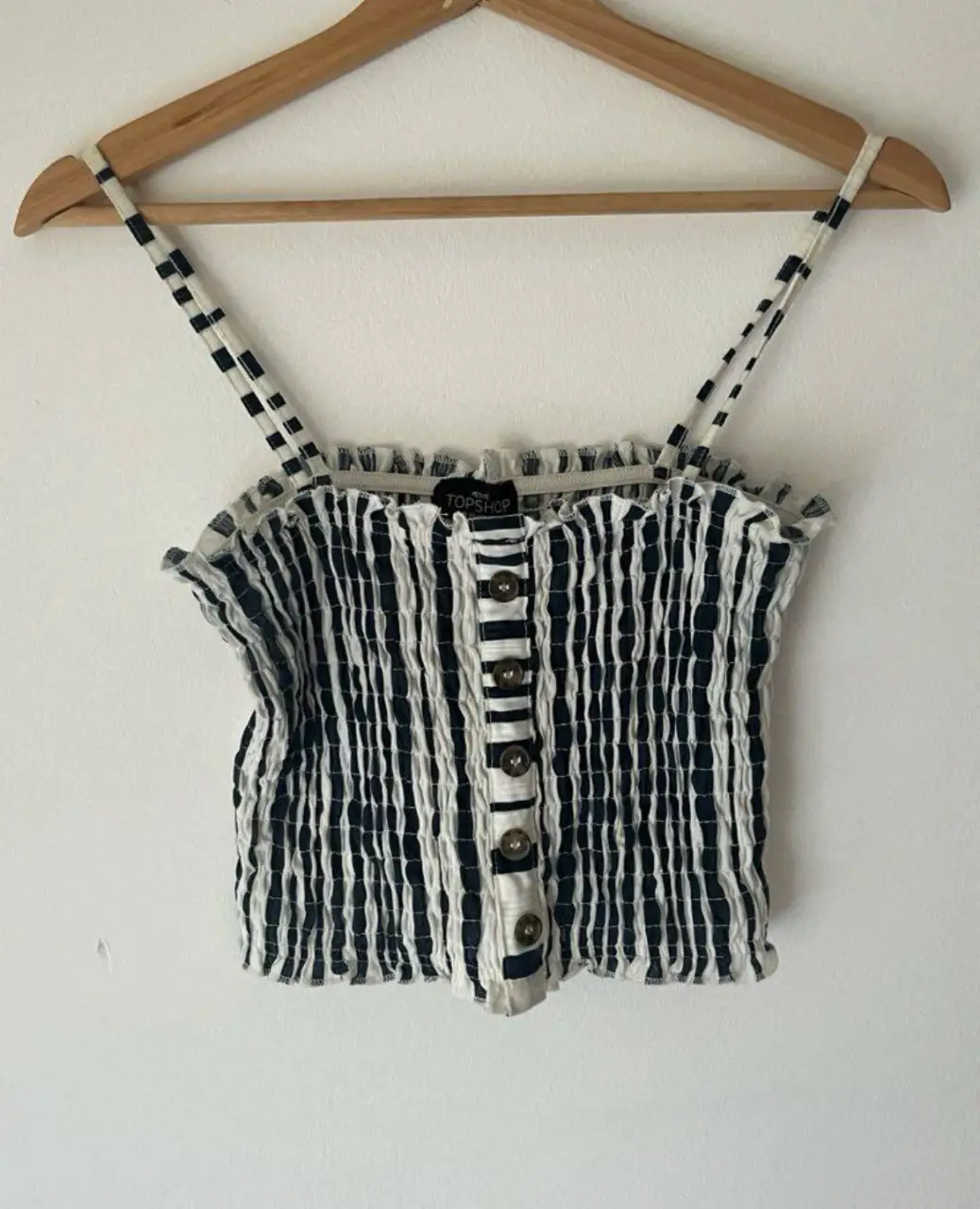 Top de mujer a rayas verticales en blanco y azul oscuro, con botones al frente y tirantes a juego. Ideal para un look casual y fresco.