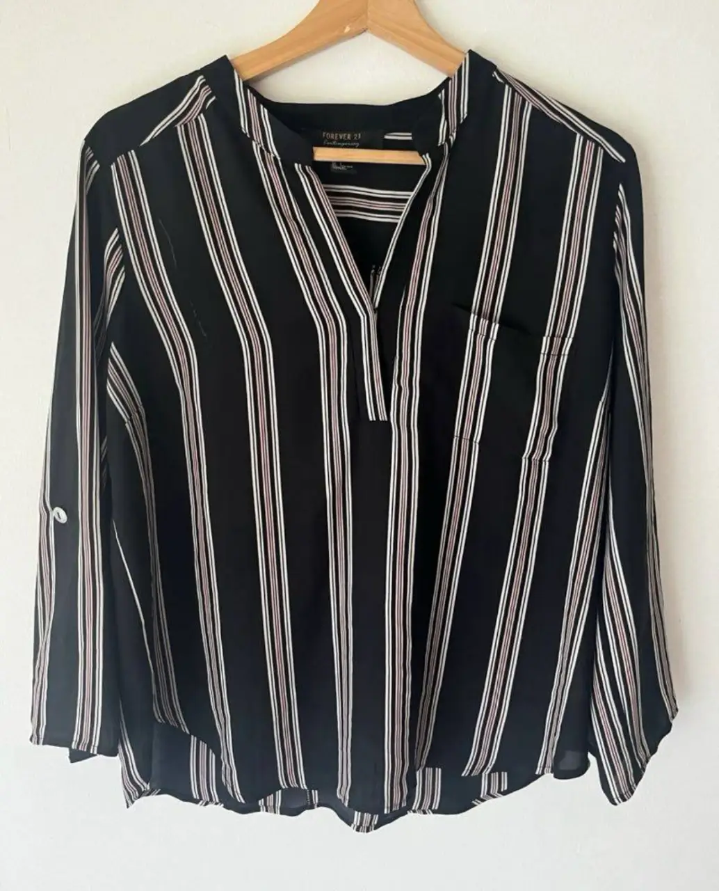 Blusa de Forever 21 Contemporary a rayas verticales en blanco, rosado y negro. Con cuello en V y bolsillo en el pecho. Manga larga con botón en el codo.