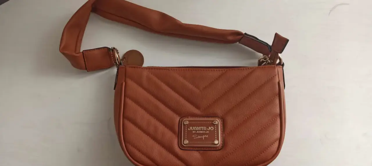 Cartera bandolera marrón con diseño acolchado en forma de chevron. Cuenta con correa ajustable y cierre superior. Ideal para un look casual y moderno.