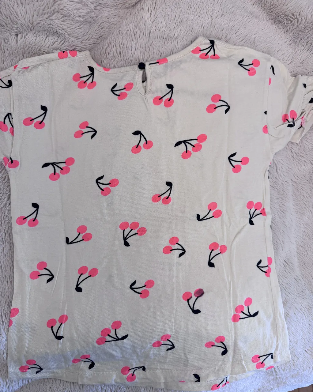 Remera de niña con estampado de cerezas rosas sobre fondo blanco. Cuello redondo y manga corta. Ideal para un look casual y fresco, dice talle 12 pero es chica .