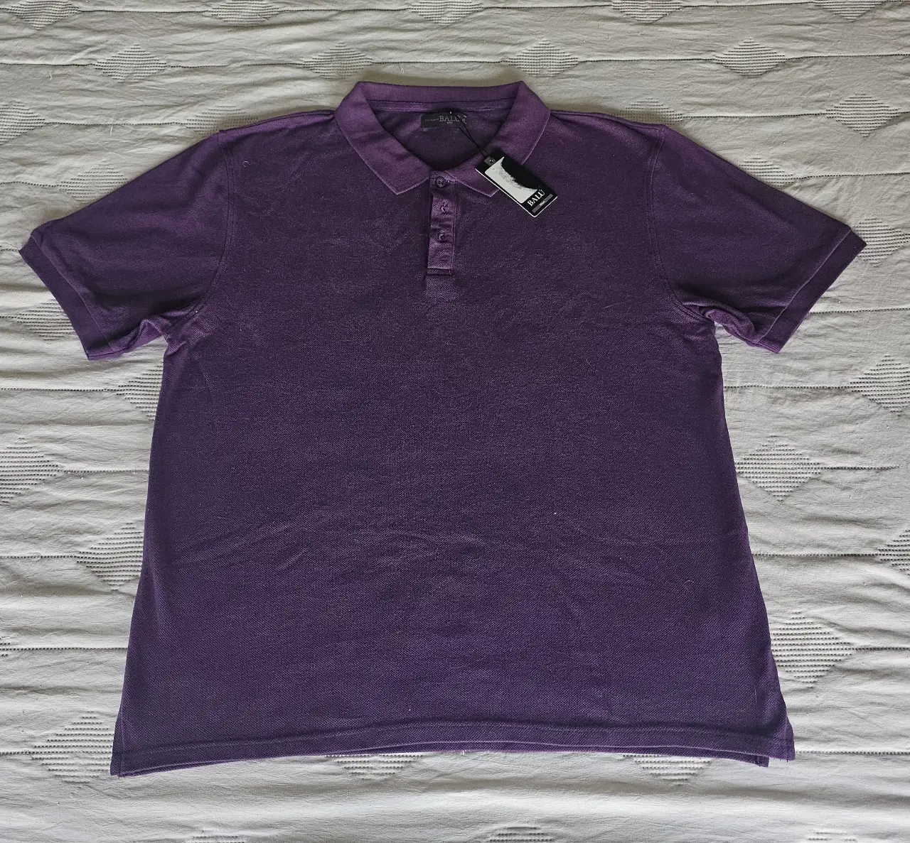 Chomba polo de hombre, color violeta, con etiqueta. Ideal para un look casual y cómodo.