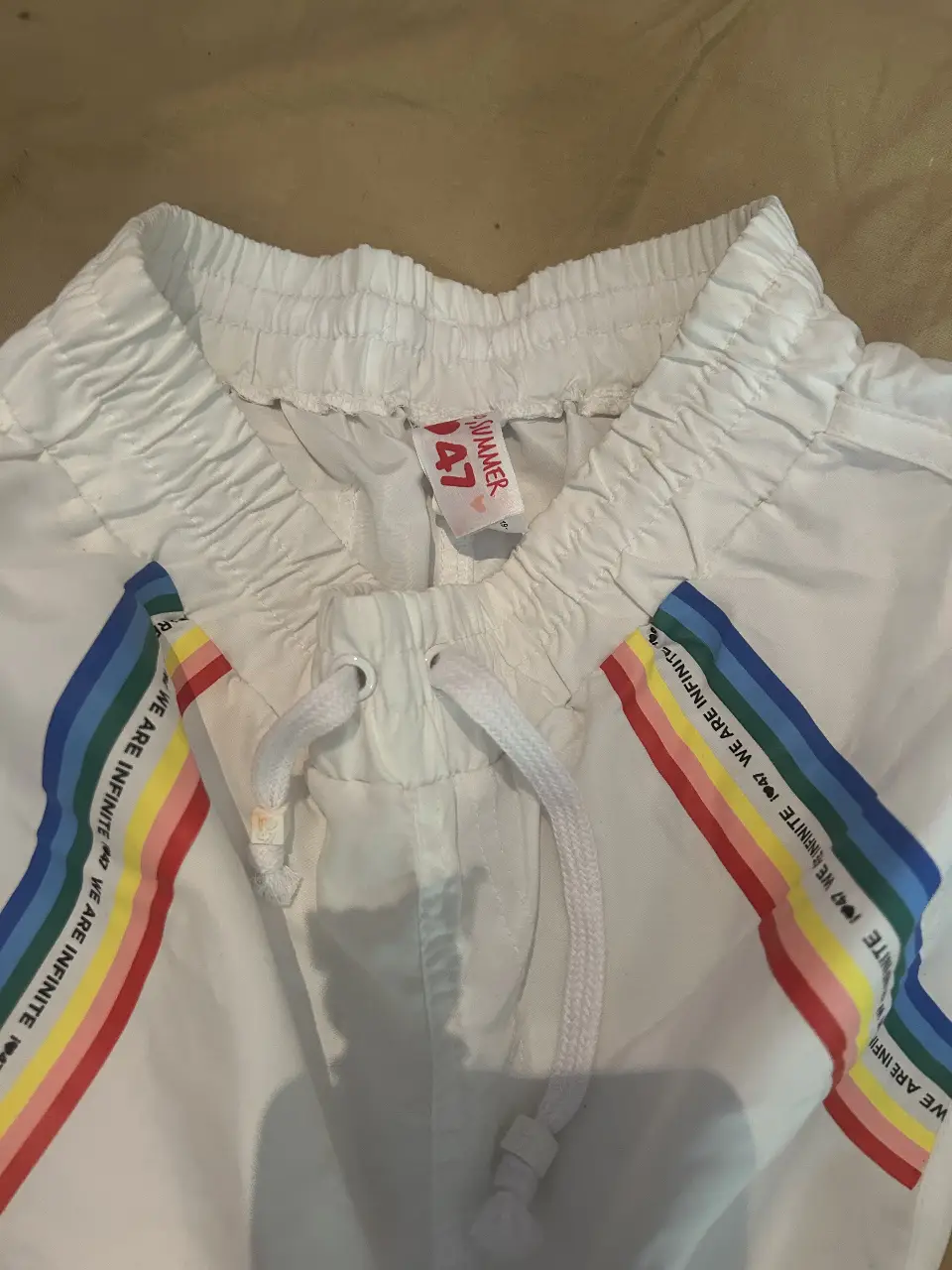 Short deportivo blanco con detalles de arcoíris en los laterales. Ideal para actividades físicas o un look casual y cómodo.