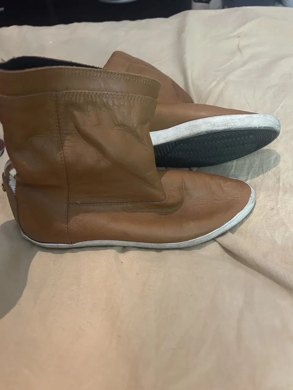 Botas Adidas de cuero marrón con detalles blancos en los laterales. Diseño moderno y cómodo, ideales para un look casual y urbano.