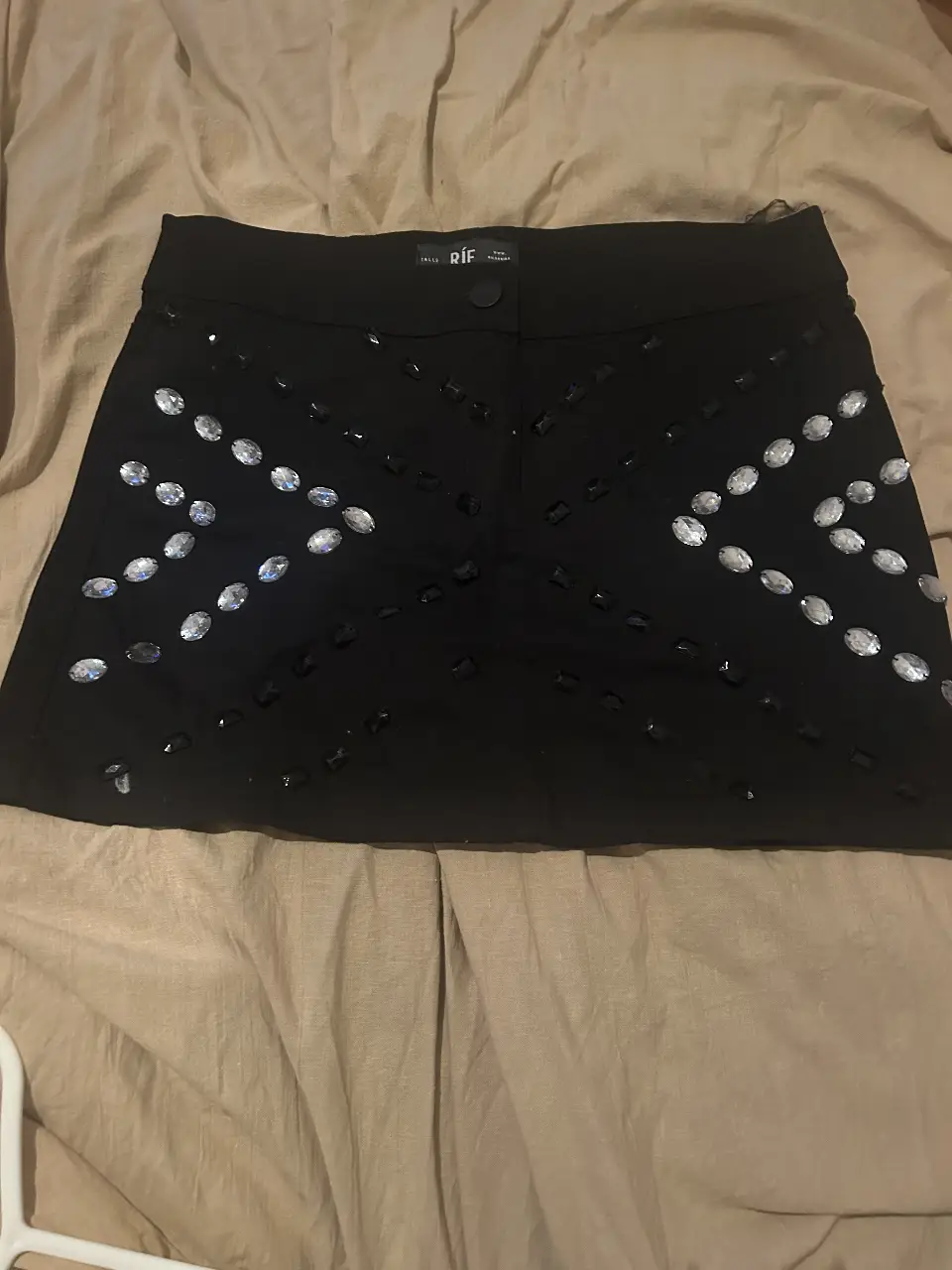 Minifalda negra con detalles de piedras brillantes. Ideal para fiestas y eventos especiales. Un toque de glamour para tu guardarropa.