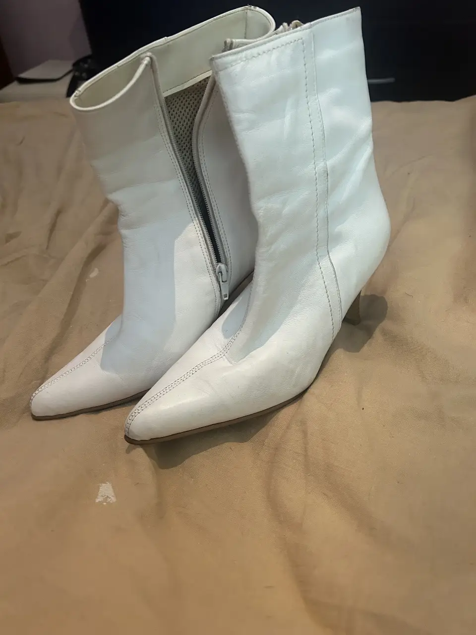 Botas blancas de cuero con taco fino y cierre lateral. Ideales para un look elegante y moderno.