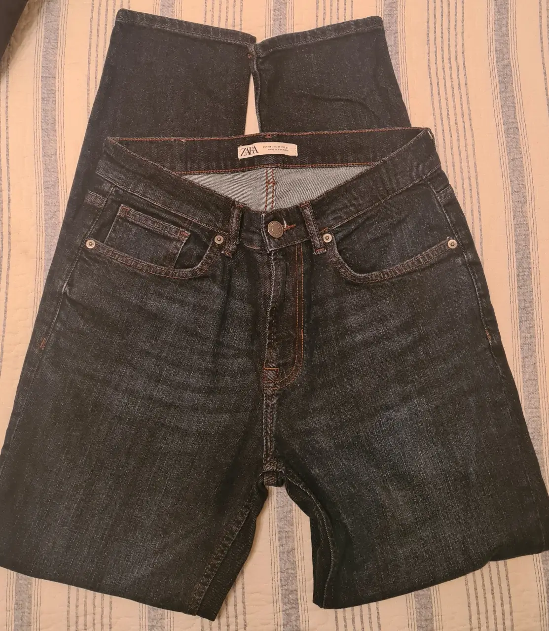 Jeans rectos de hombre, color azul oscuro, con detalles de costura en naranja. Marca Zara.