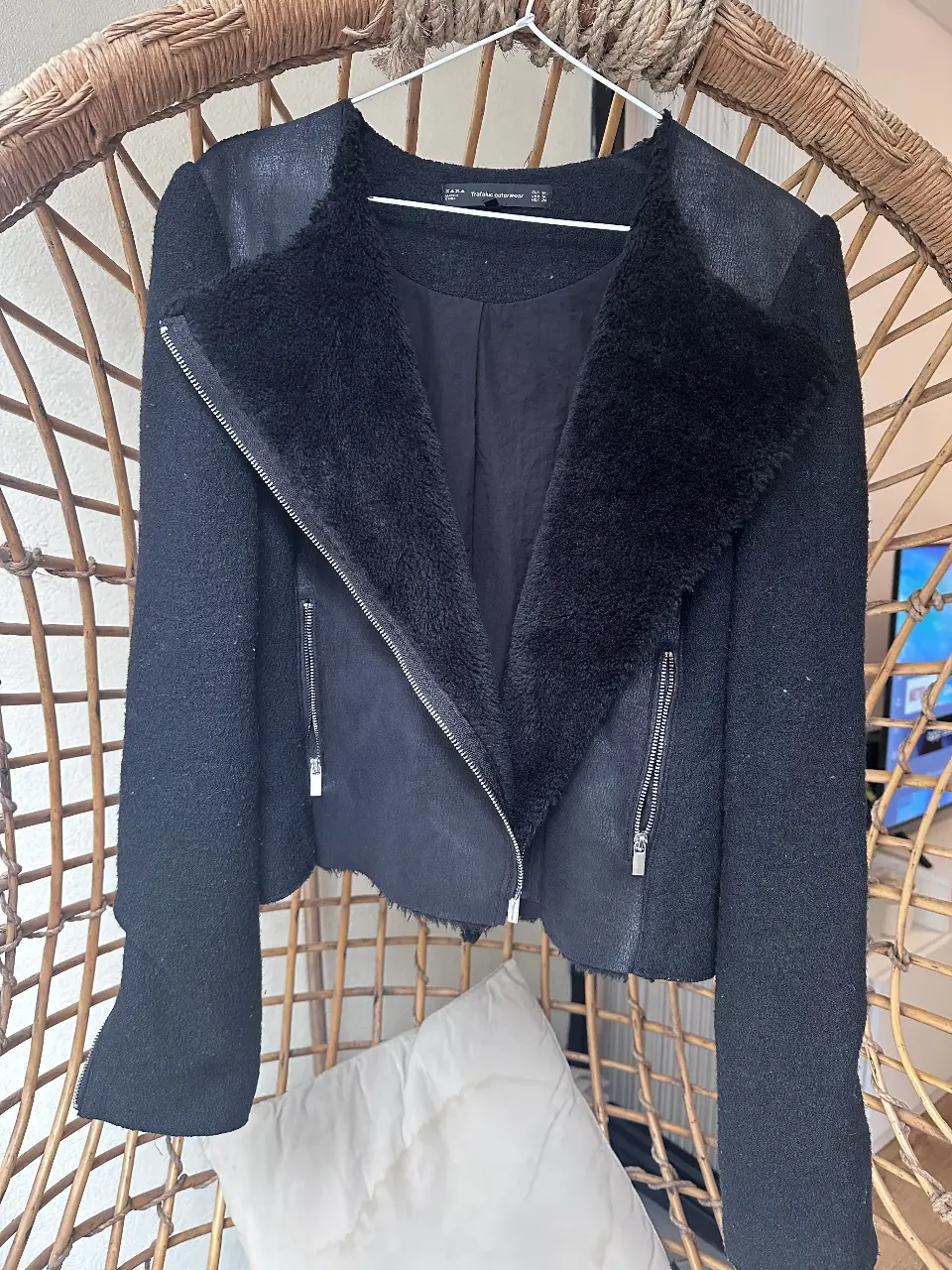 Campera Zara biker de mujer, color negro, con detalles de piel sintética en el cuello y solapas. Cierre asimétrico y bolsillos con cierres. Ideal para un look moderno y abrigado.
