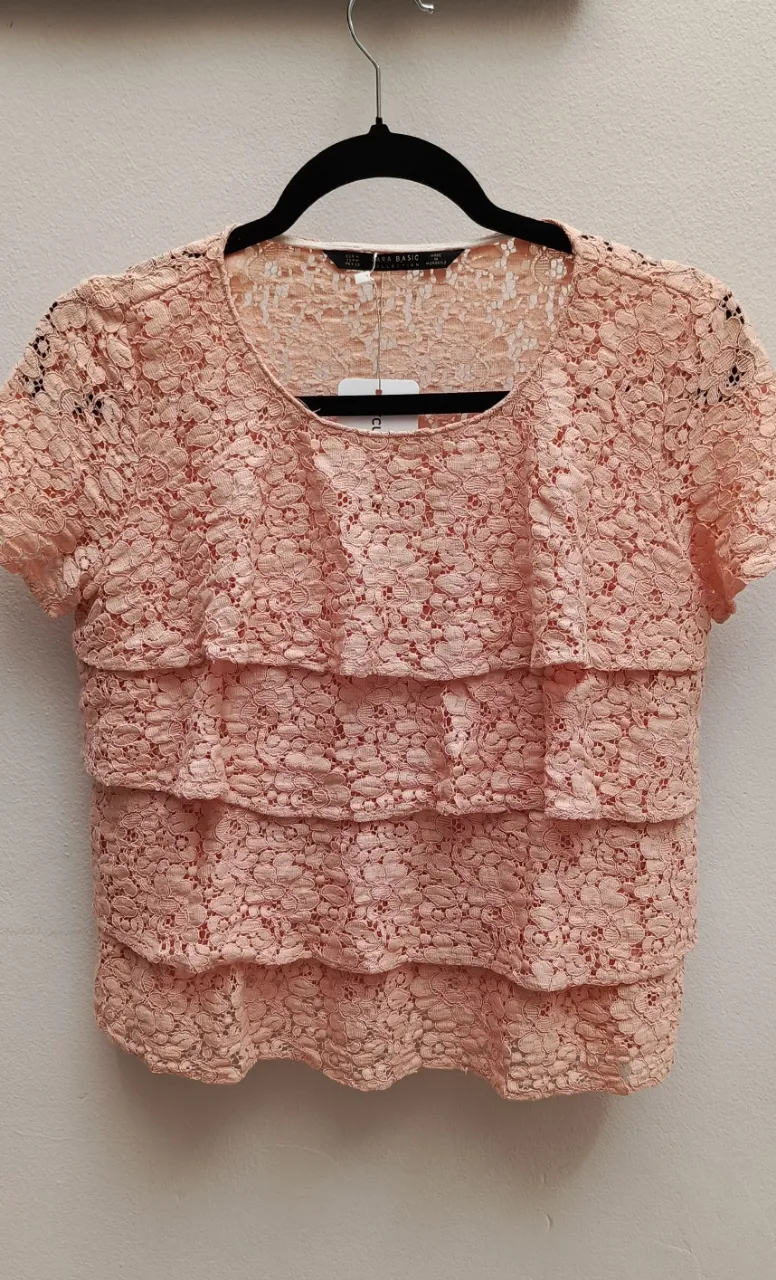 Remera rosa de encaje con volados en cascada en el frente. Mangas cortas.