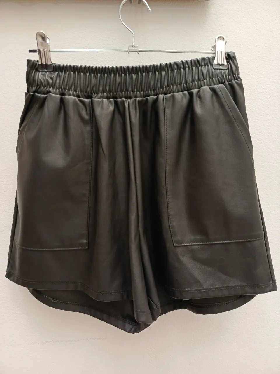 Shorts de cuero sintético negro con cintura elastizada y bolsillos frontales.