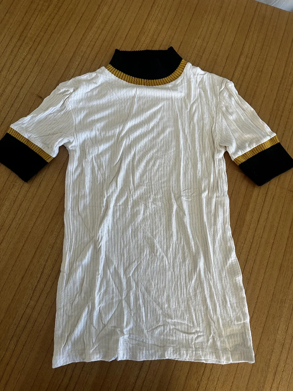 Remera de cuello alto con detalles en negro y dorado. Ideal para un look casual y moderno. Zara Turquía 