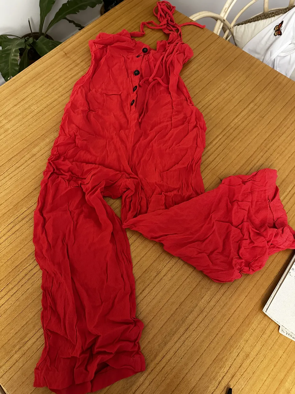 Mono plisado largo de tela roja, con botones en la parte delantera y tirantes ajustables. Ideal para un look casual y cómodo.