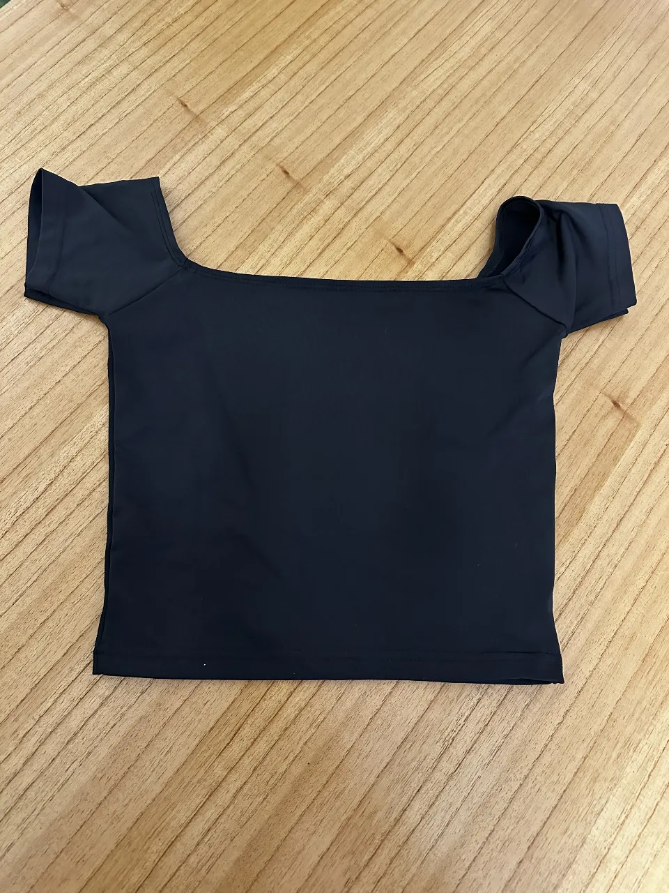 Top negro con escote cuadrado y mangas cortas. elastizado.  Ideal para un look moderno y versátil.