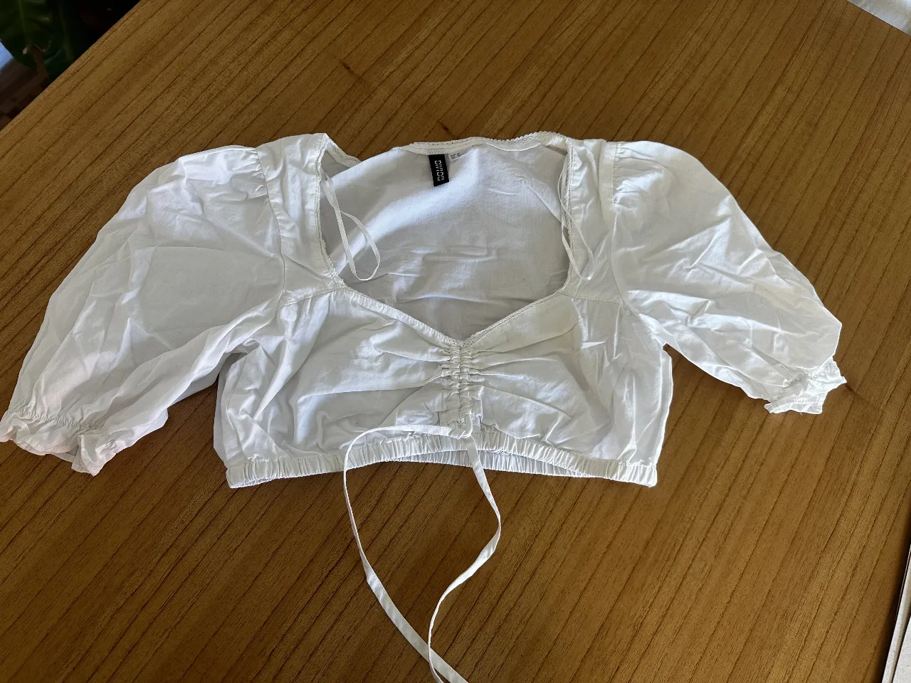 top blusa boho romántica blanca de mujer, con mangas cortas abullonadas y detalle fruncido en el centro. Ideal para un look fresco y femenino. traído de Divided España. 