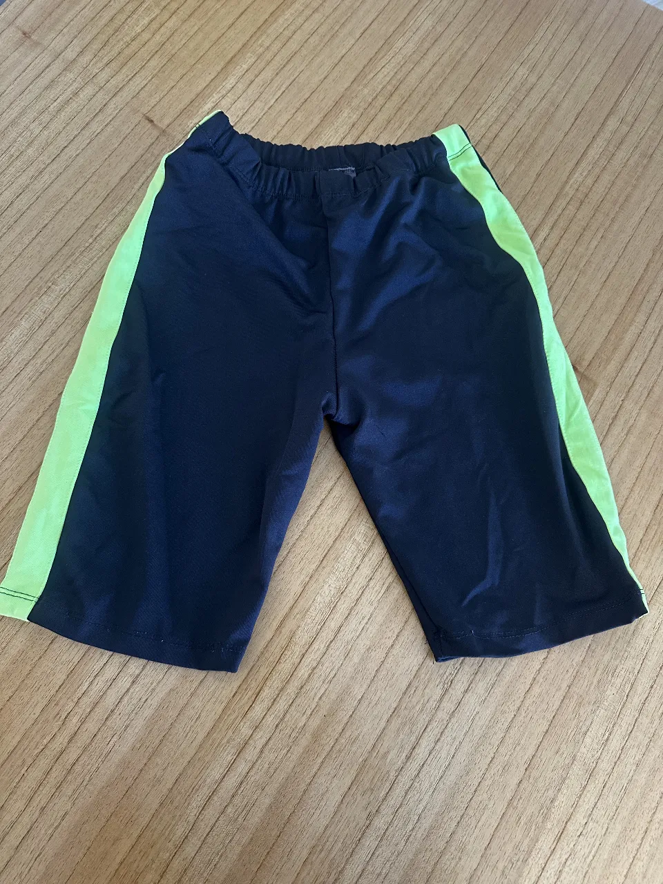 Biker deportivo negro con detalles en verde. Ideal para actividades físicas.