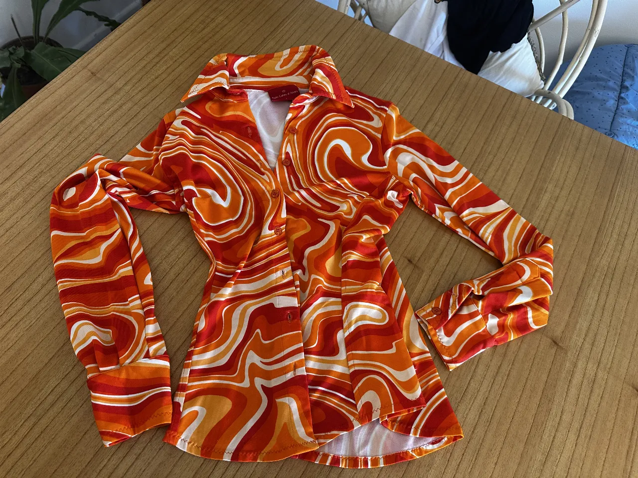 Camisa vintage de los 90 de Paula Cahen DAnvers estampada con diseño psicodélico en tonos naranja y blanco. Corte cenido en cintura con cuello camisero y mangas largas con puños. Ideal para un look retro y llamativo.