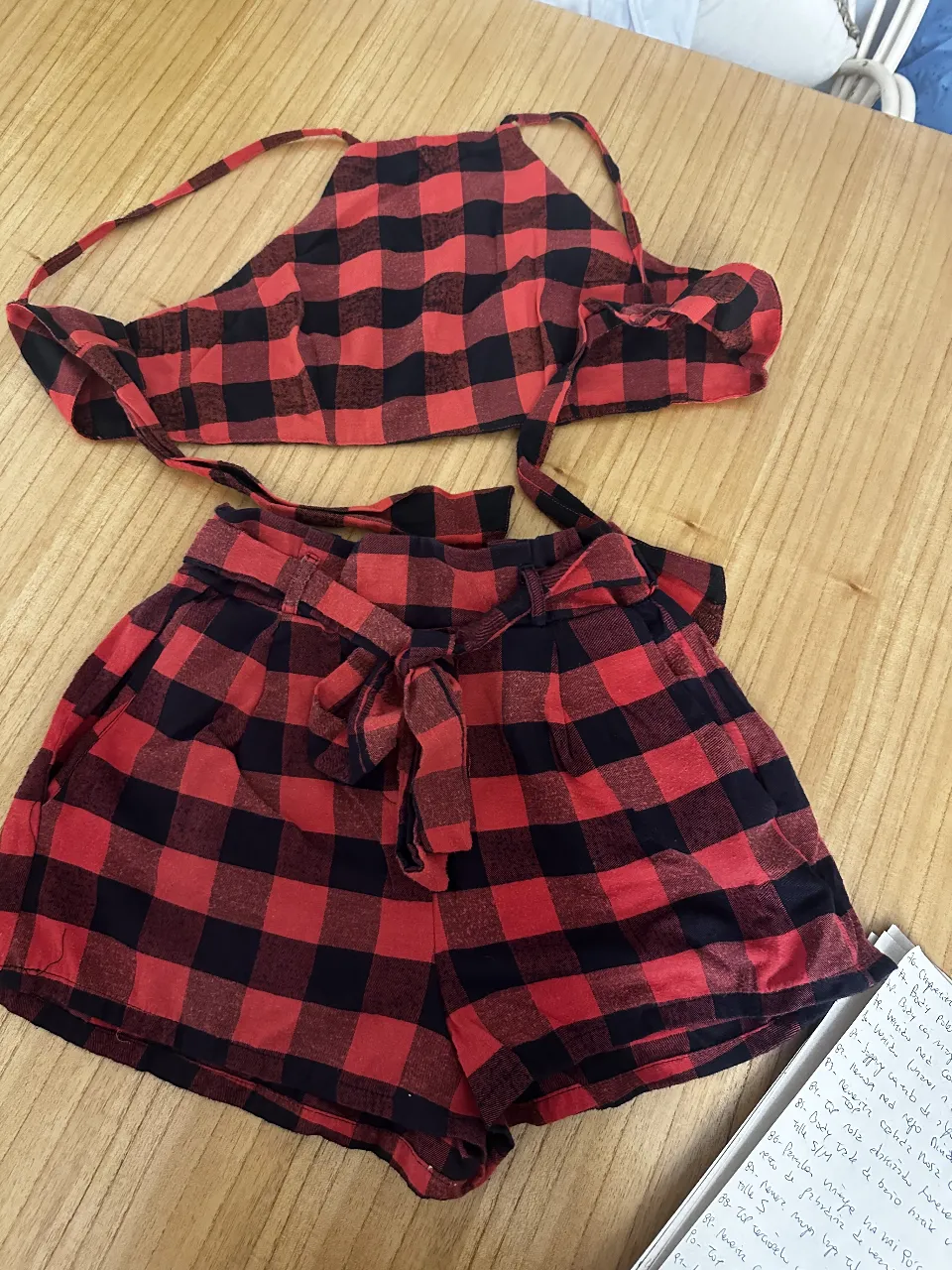 Conjunto de top halter y short a cuadros rojos y negros. El top se ata en la espalda y el short tiene cintura alta con lazo.