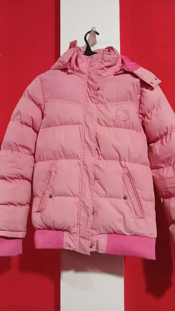 Campera de pluma rosa para niña con capucha y detalle de Hello Kitty. Ideal para el invierno, abrigada y con puños tejidos.
