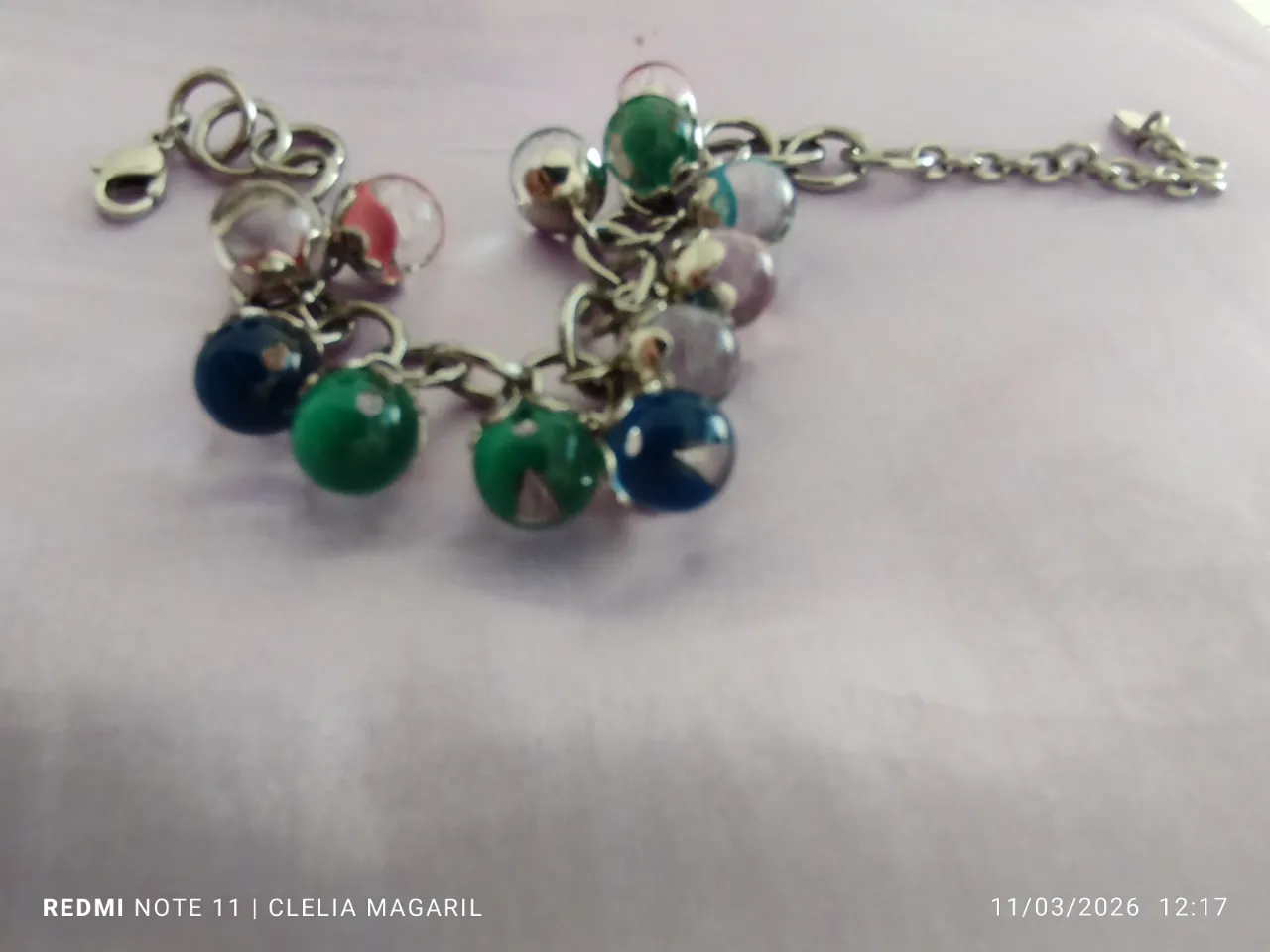 Pulsera de eslabones plateados con dijes de bolitas de vidrio que  cambian de colores según la luz y con cierre tipo mosquetón.