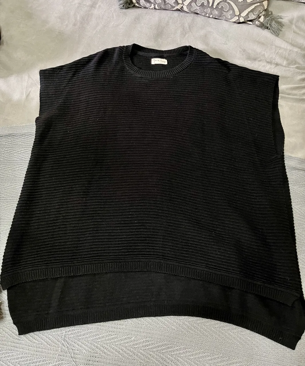 Chaleco negro de tejido acanalado, sisas profundas y más largo en espalda. Oversize, ideal para llevarlo con camisa debajo. 