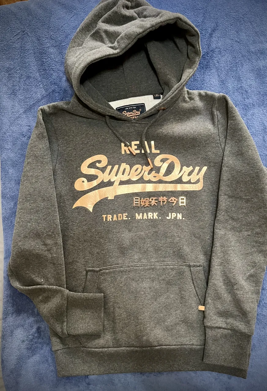 Hoodie gris Impecable! ⭐️ Superdry, con estampa frontal en dorado y apliques en relieve. 