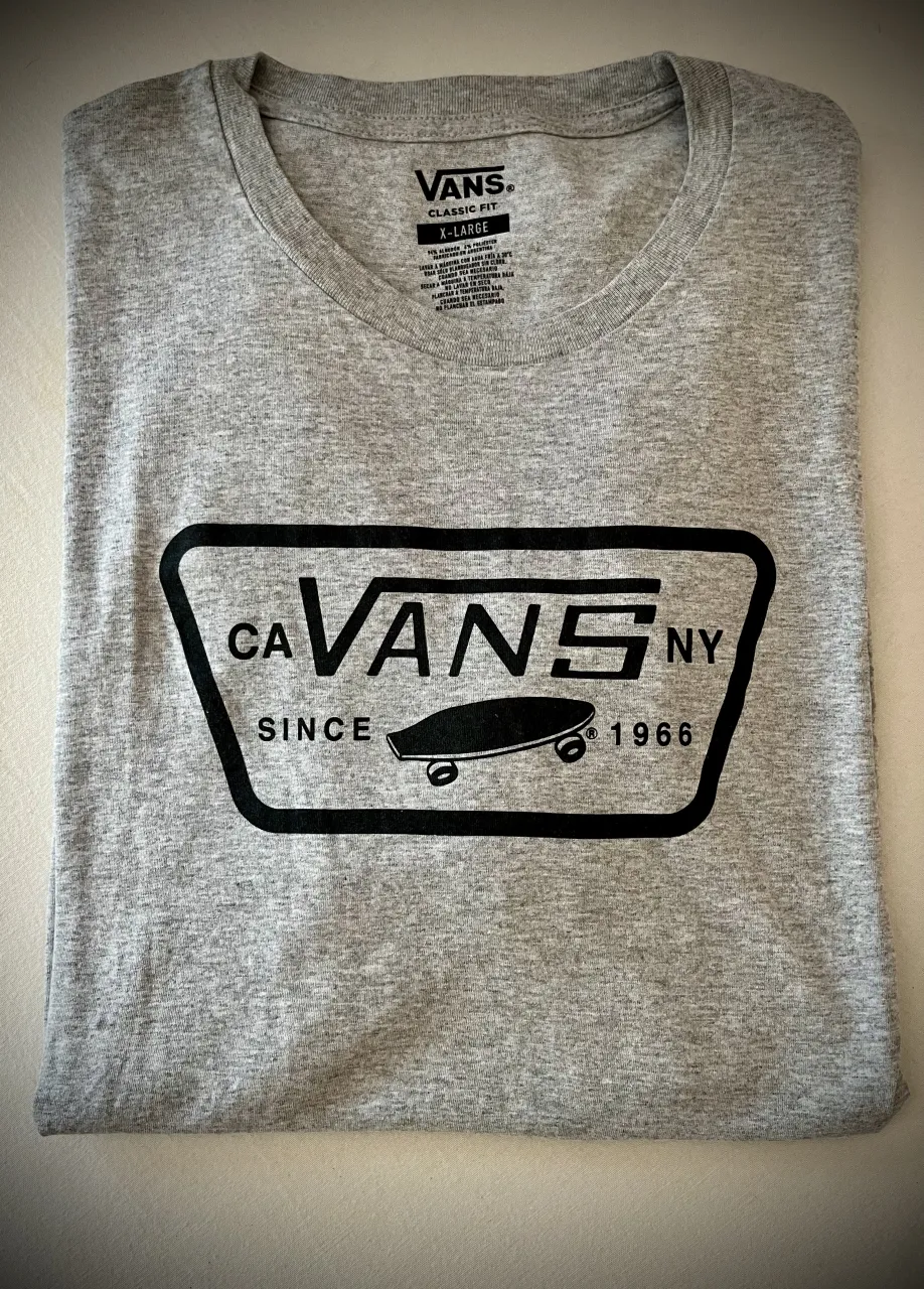 Remera gris 🩶, básica de manga corta con estampa del logo Vans en negro en el frente. Cuello redondo. Fit holgado. 