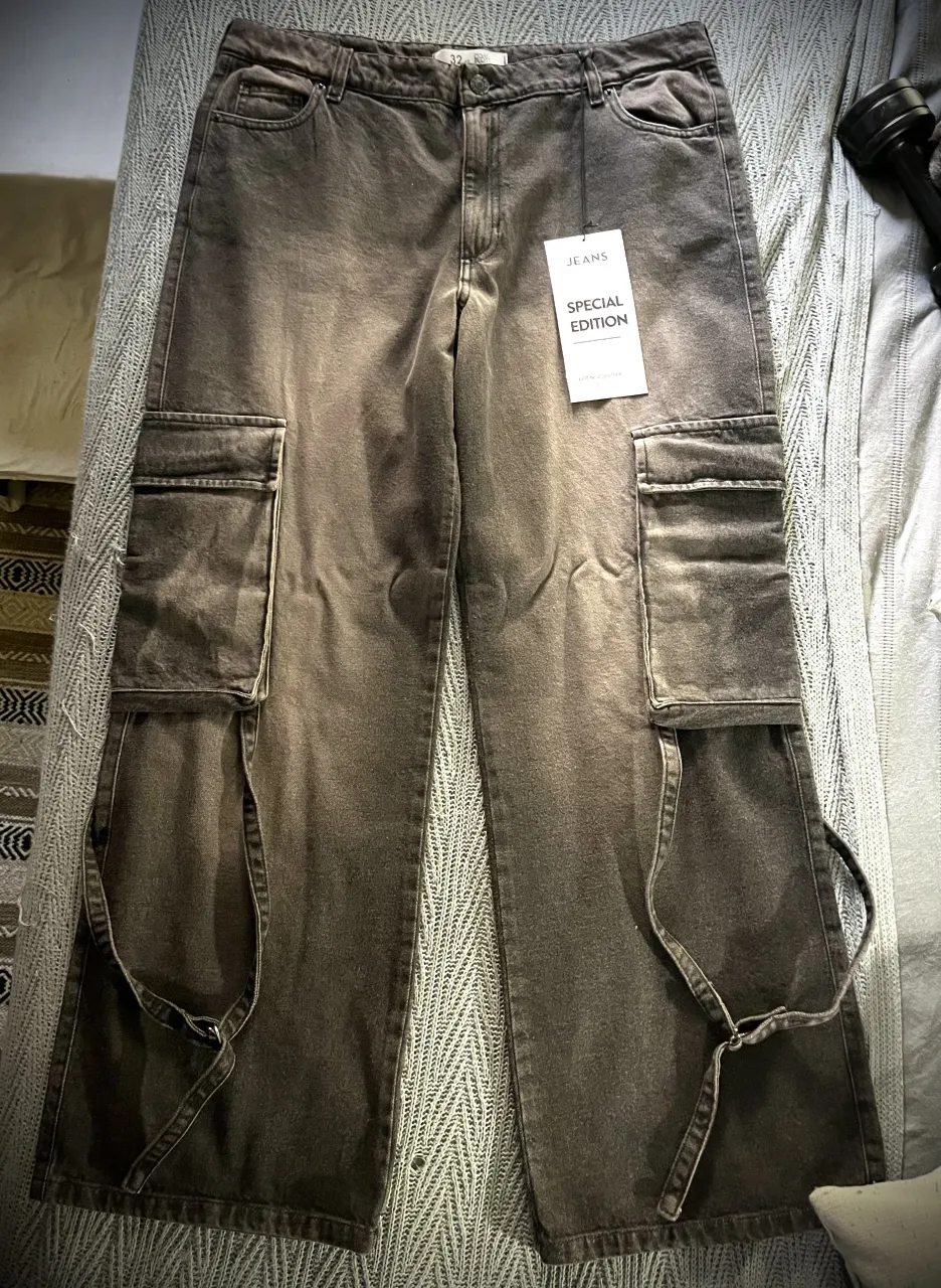 Pantalón Nuevo!!! 🖤 Cargo de jean color gris oscuro con proceso de desgaste, tiene bolsillos amplios en los laterales por debajo de la segunda cadera y tiras ajustables desde los bolsillos. Bolsillos traseros con tapa. Fit holgado. 100% algodón. Unisex. 