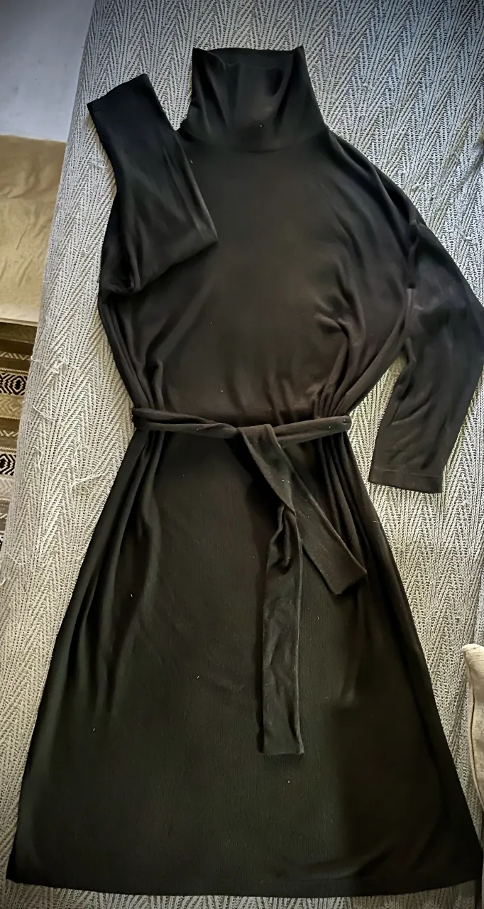 Vestido negro 🖤, de manga larga con cuello alto y cinturón en el mismo género de uso optativo. Largo por debajo de las rodillas. Tajos en los laterales (ver foto). 
Fit holgado. 96% rayón. 