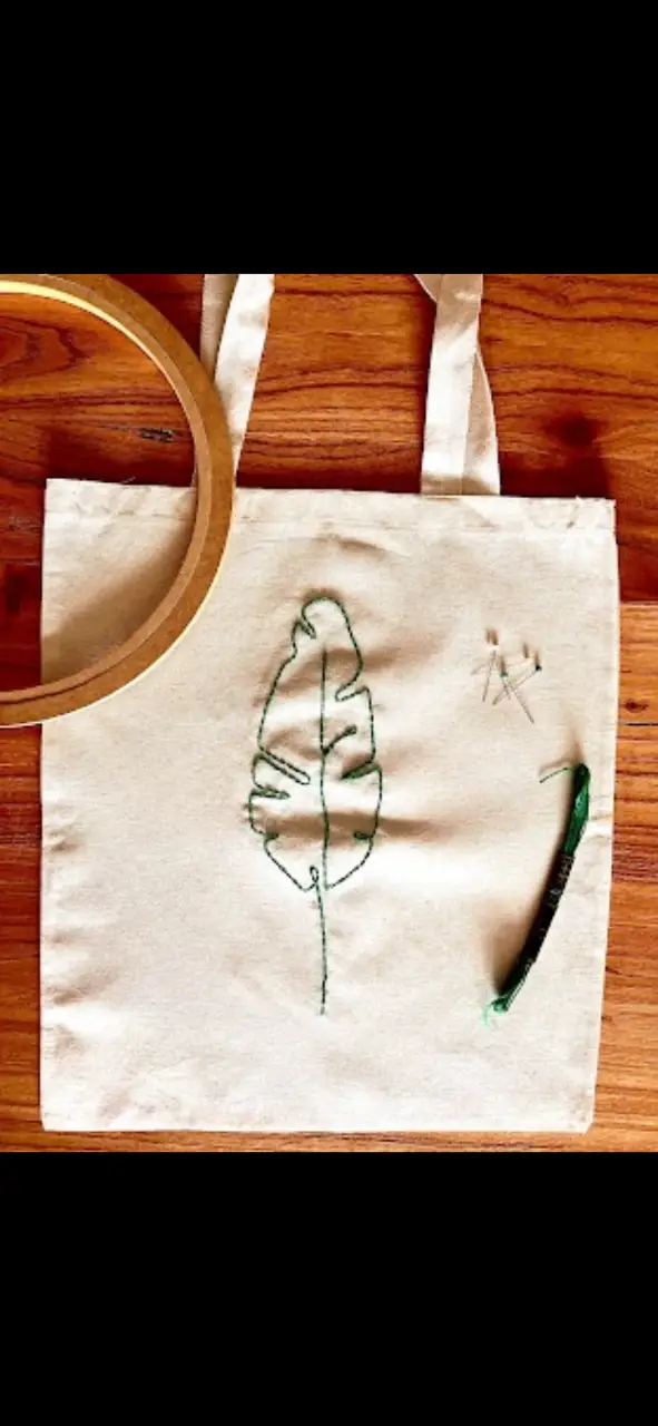 Bolso tote bag de tela cruda con diseño de hoja bordada en verde. Ideal para llevar tus cosas con estilo y un toque artesanal.