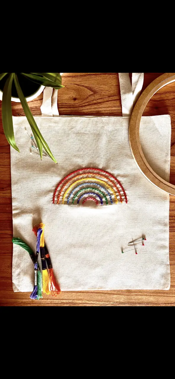 Bolso tote bag de tela cruda con bordado artesanal de arcoíris. Ideal para llevar tus cosas con estilo y un toque de color.