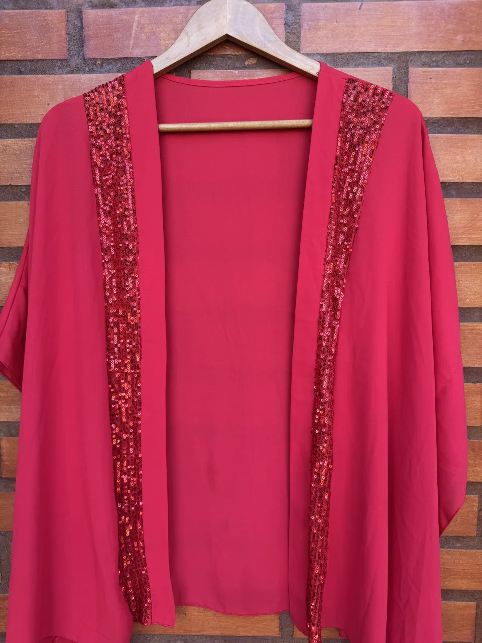 Kimono rosa vibrante con detalles de lentejuelas brillantes en los bordes. Una prenda ideal para darle un toque de glamour a cualquier outfit, perfecta para eventos o salidas nocturnas.