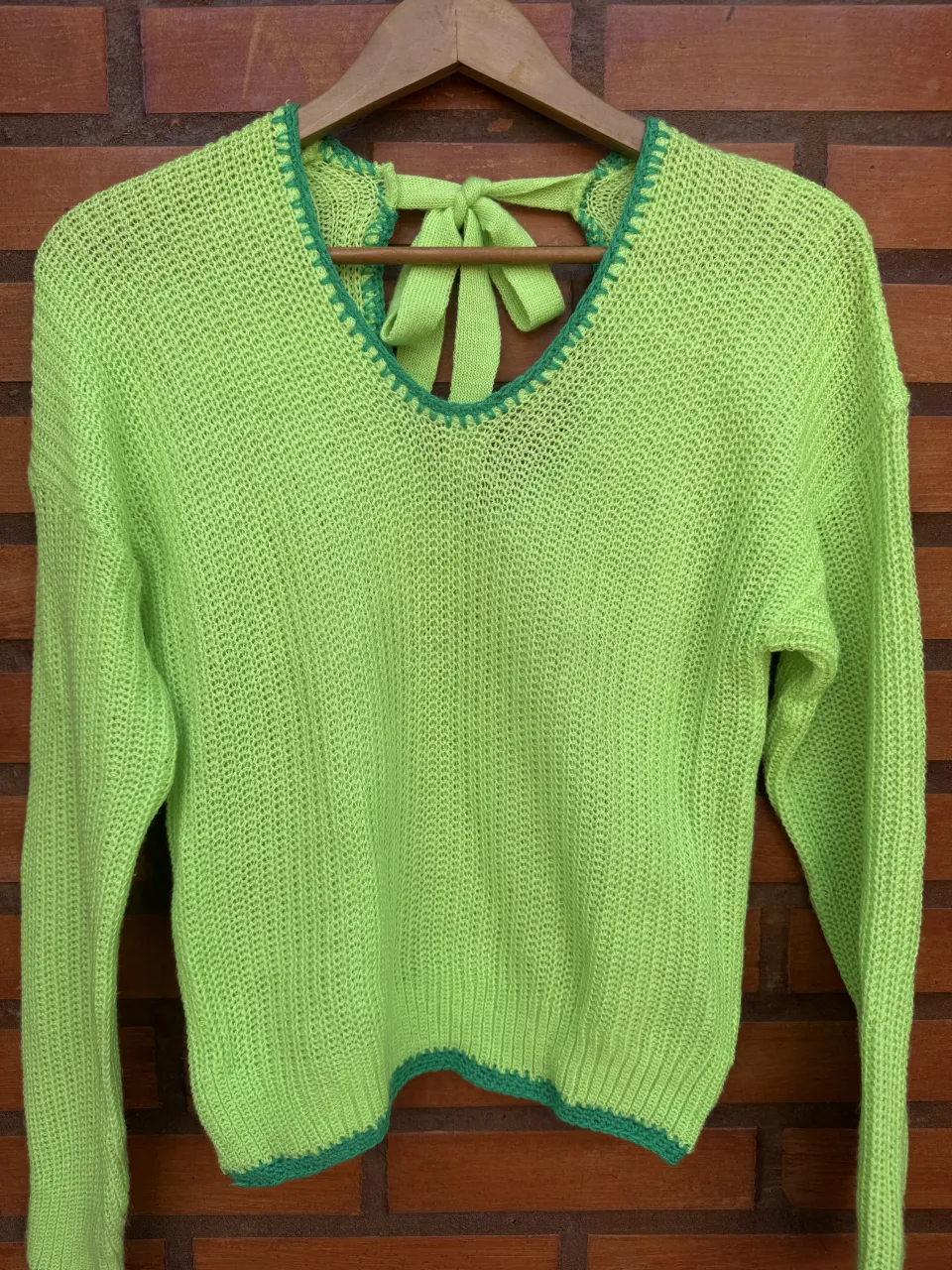 Sweater tejido color verde lima con detalle de lazo en la espalda. Escote en V y terminaciones en crochet.