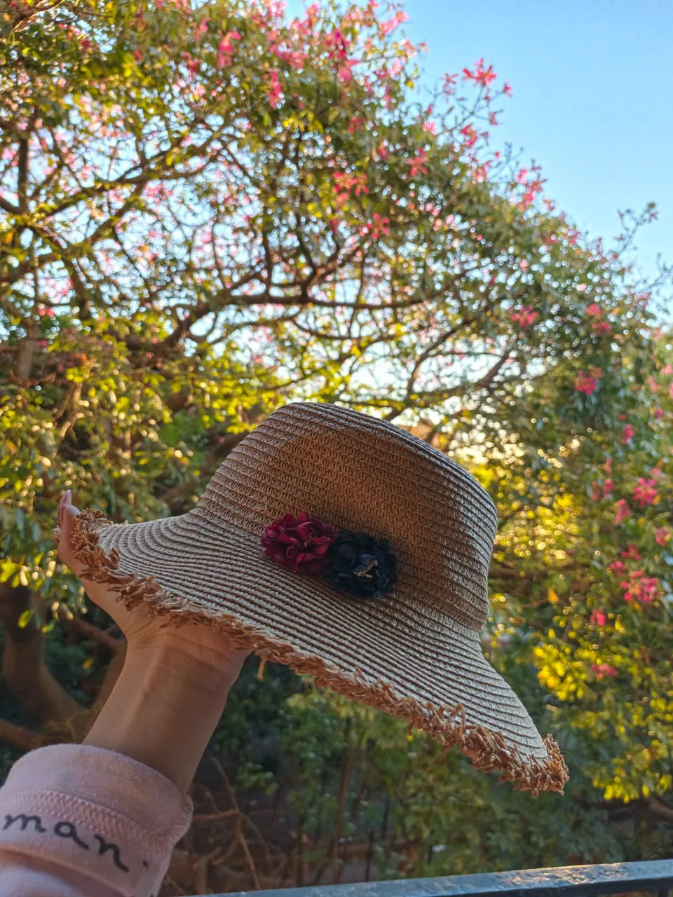Sombrero de paja tejido con detalle de flores en la base de la copa. El borde de la copa y el ala tienen un acabado deshilachado. Ideal para la playa o simplemente para protegerse del sol y complementar tu look🤍